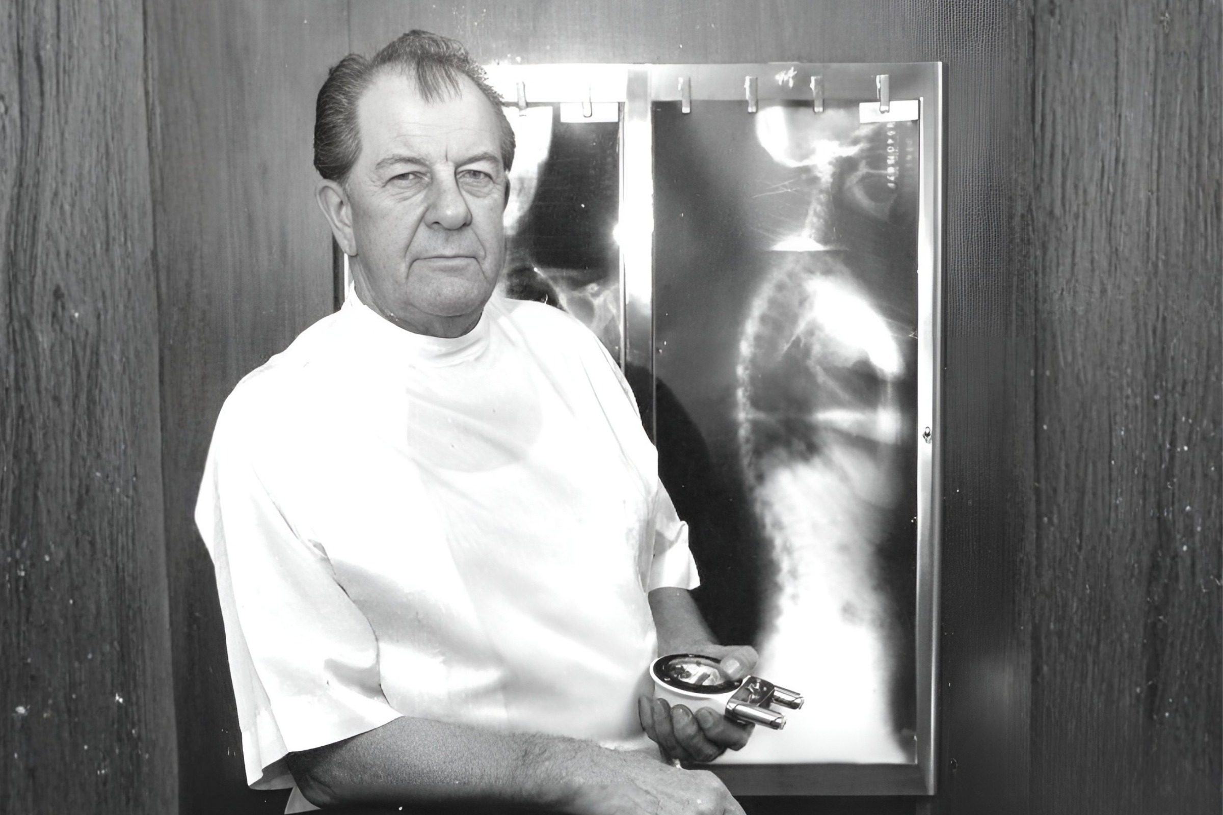 Dr. Clarence Gonstead holding a Nervo-Scope beside a full-spine X-ray